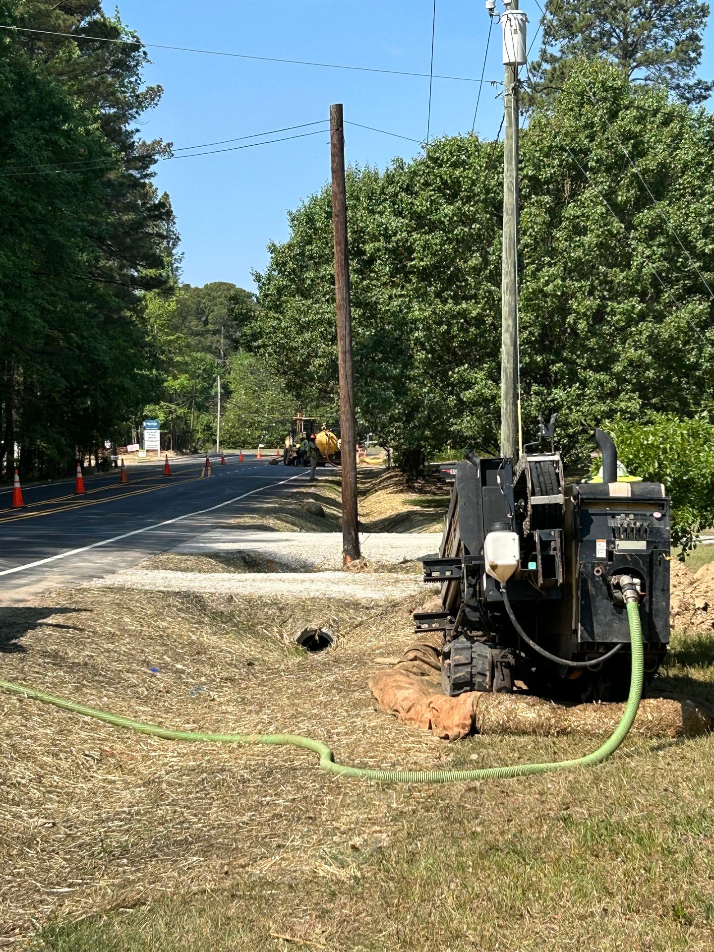 Horizontal directional drilling rig boring conduit beside a utility pole and overhead power lines
