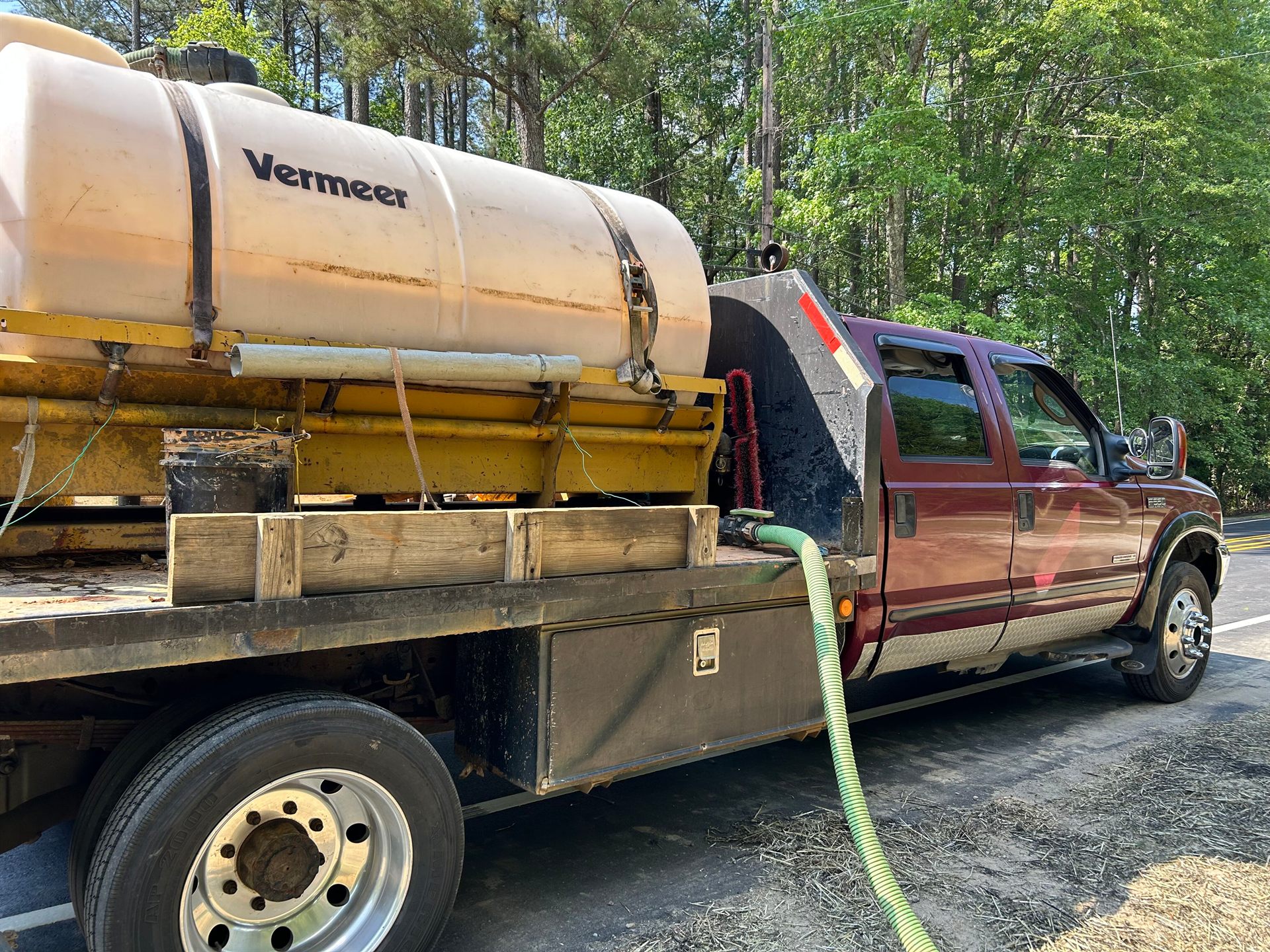 Flatbed truck hauling a Vermeer drilling-fluid tank used for horizontal directional drilling