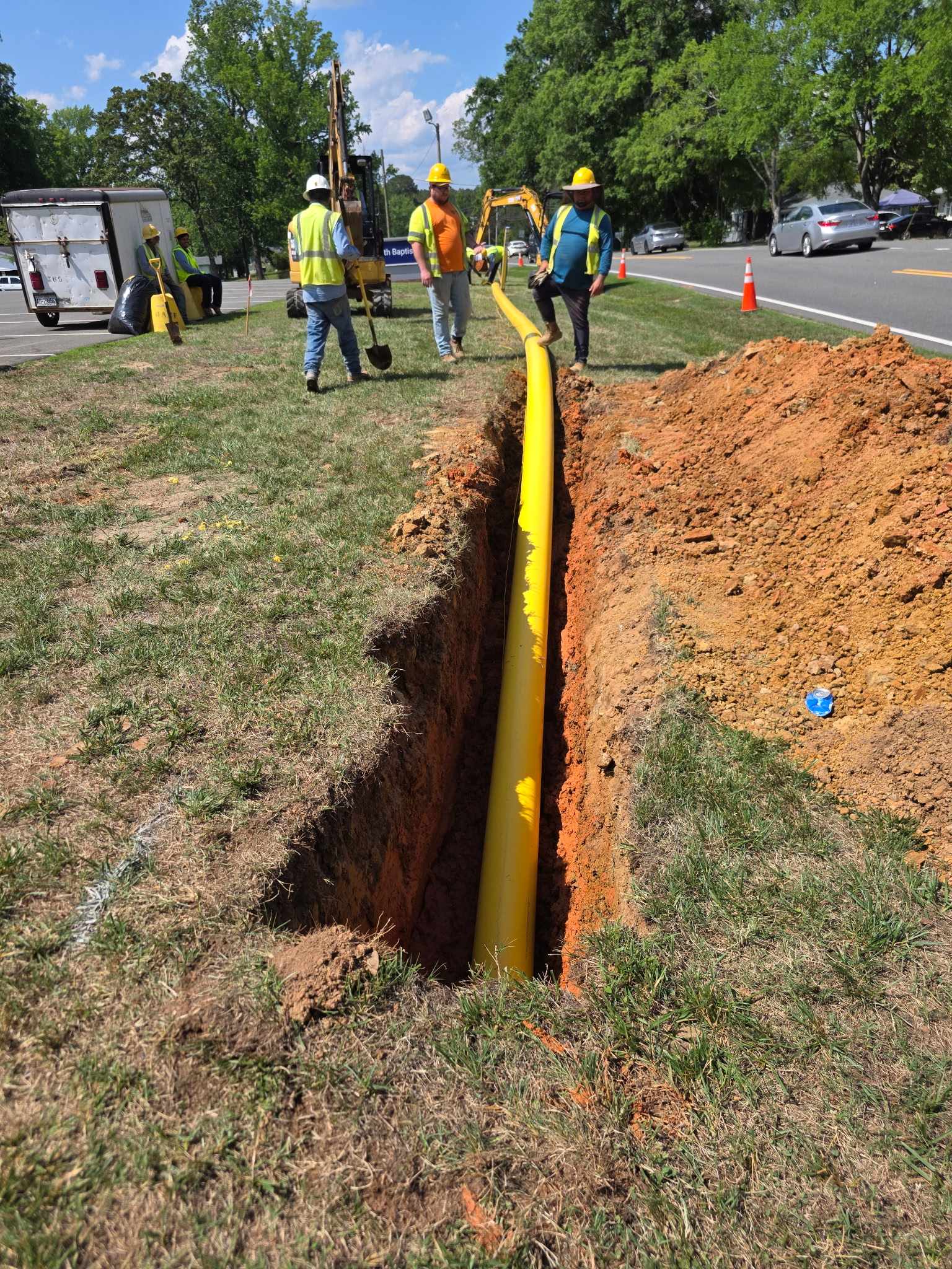 Triple J Specialist crew installing a yellow gas line in a roadside trench