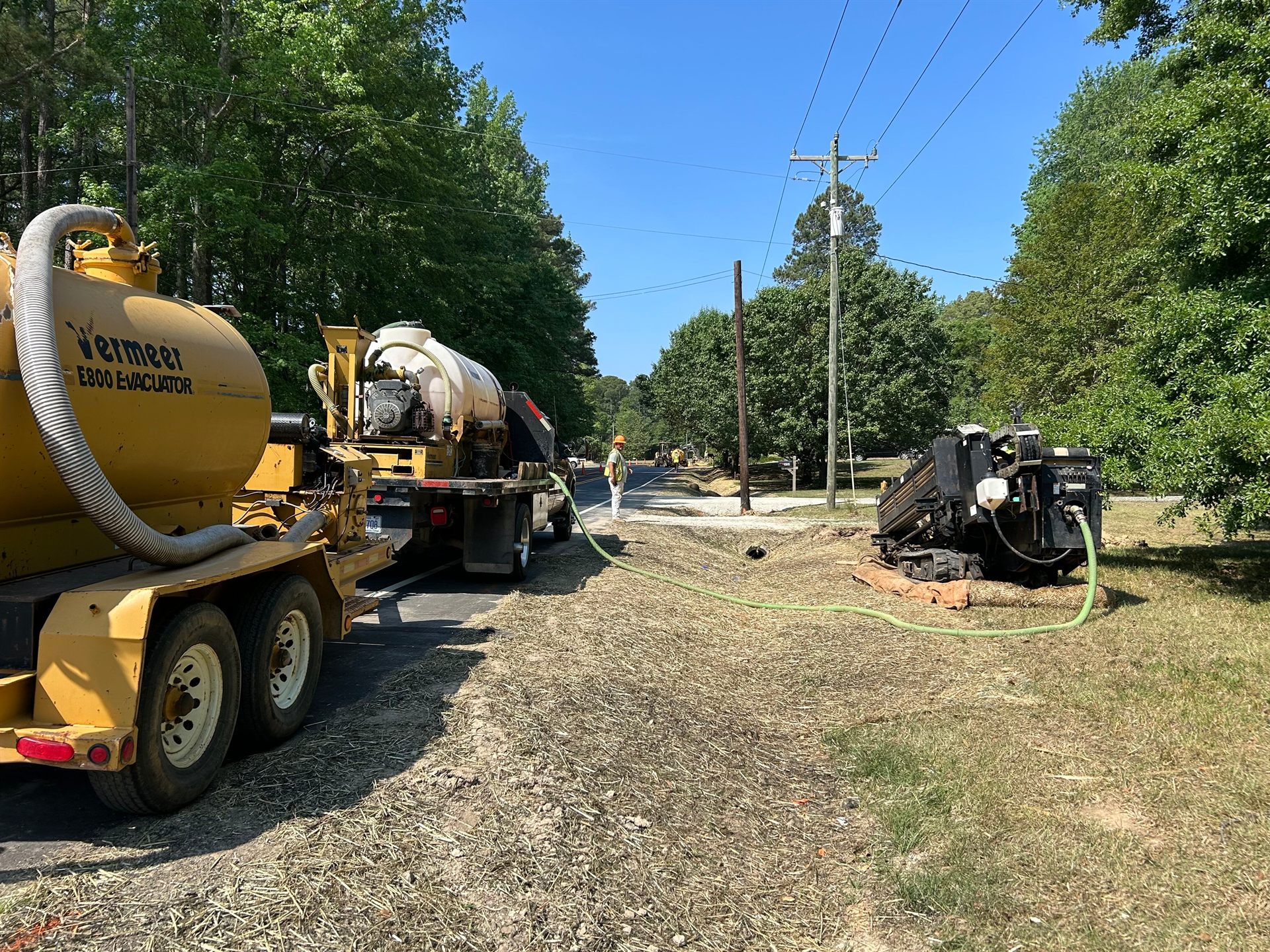 Directional drilling job site with a vacuum excavator and drill rig staged along a residential street